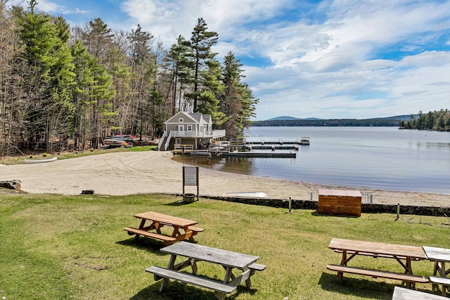 view of property's community featuring a lawn, a water view, and a dock