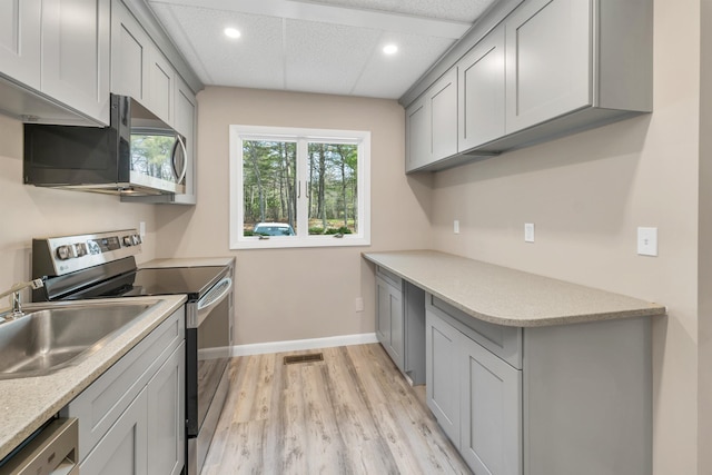 kitchen featuring visible vents, light countertops, gray cabinets, light wood-style flooring, and stainless steel appliances