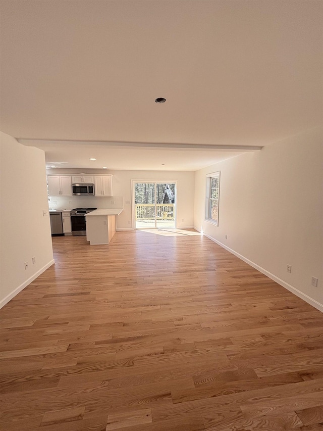 unfurnished living room with recessed lighting, baseboards, and light wood-style flooring