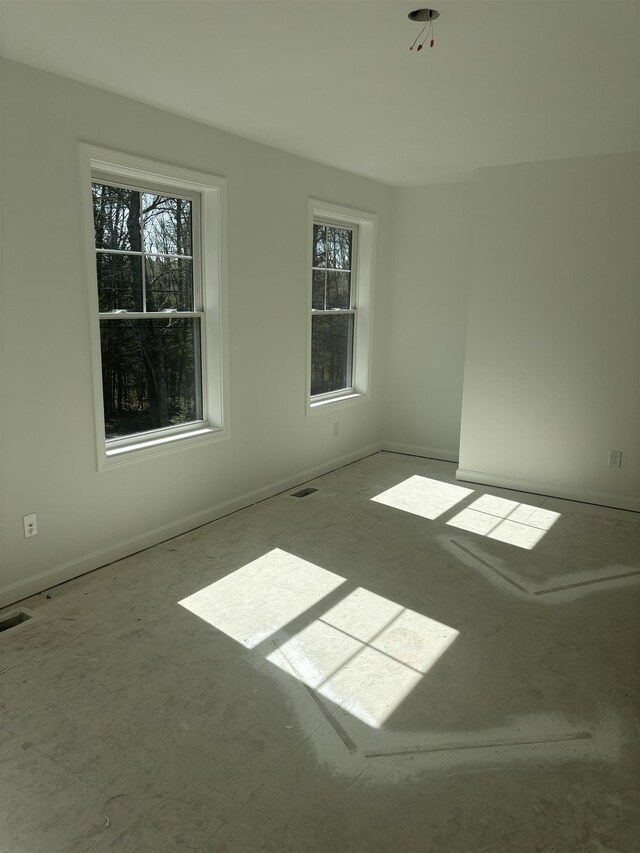 empty room with baseboards, visible vents, and a wealth of natural light