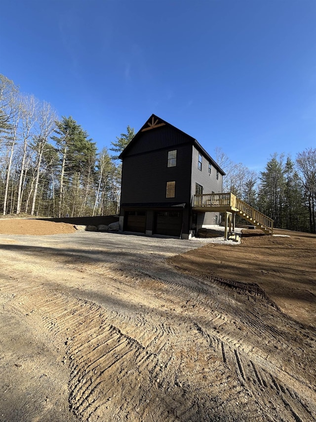 view of home's exterior featuring an attached garage, a wooden deck, driveway, and stairway