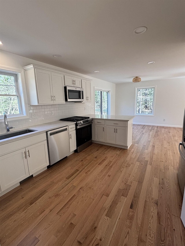 kitchen with light wood-type flooring, white cabinetry, tasteful backsplash, and stainless steel appliances