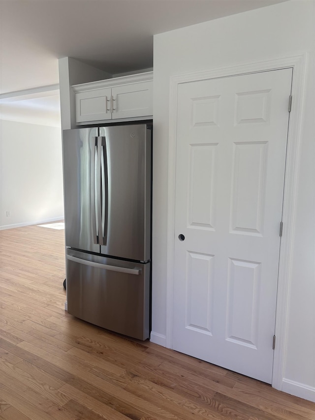 kitchen featuring baseboards, freestanding refrigerator, wood finished floors, and white cabinets