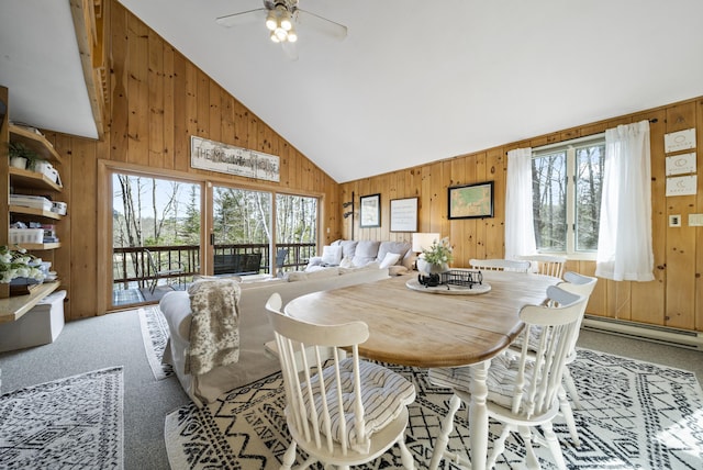 dining room featuring wood walls, ceiling fan, baseboard heating, and carpet flooring