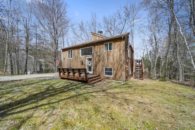 back of house featuring stairs, a chimney, a yard, and a deck
