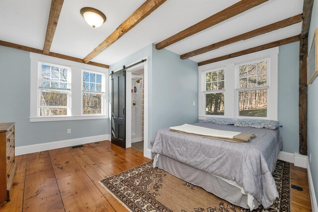 104 Pease Rd, Meredith, NH 03253 - bedroom with beamed ceiling, baseboards, a barn door, and hardwood / wood-style floors