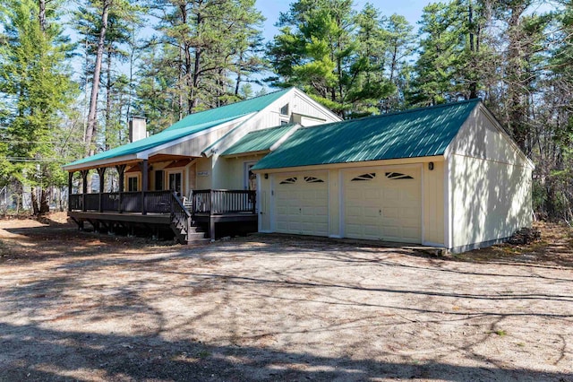 view of front of property with a chimney, metal roof, and a garage