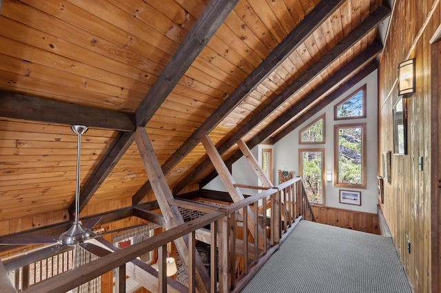 hallway featuring wooden walls, wooden ceiling, lofted ceiling with beams, and an upstairs landing