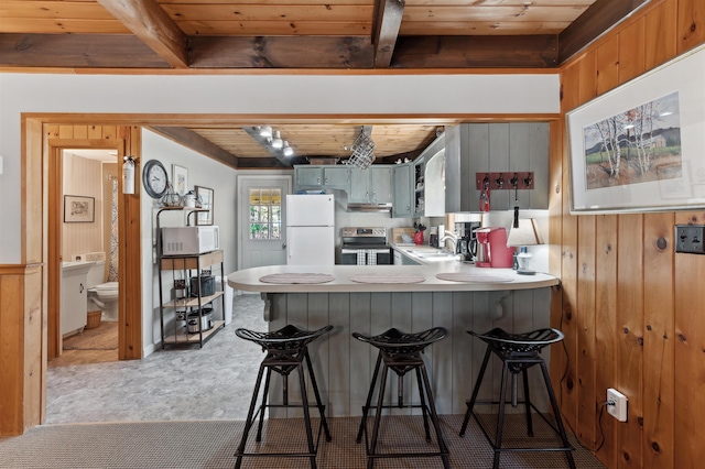 kitchen featuring beam ceiling, a sink, wooden ceiling, a peninsula, and white appliances