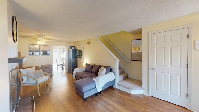 living room featuring stairs, a ceiling fan, and wood finished floors