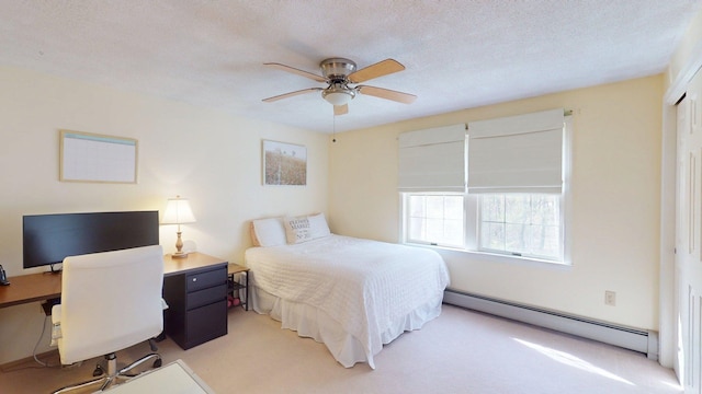 bedroom with ceiling fan, light carpet, a textured ceiling, a baseboard heating unit, and a closet