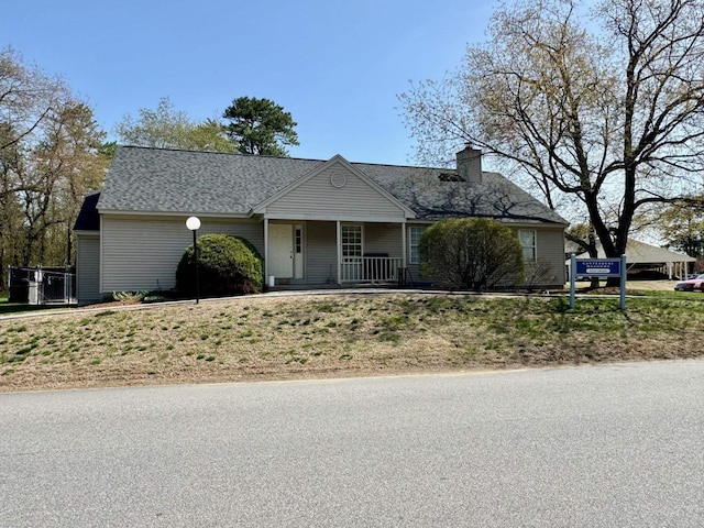 view of front facade featuring a porch and a chimney