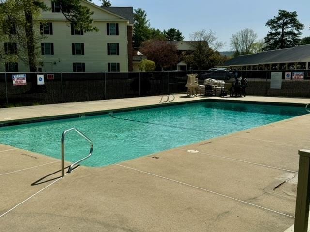 community pool with fence and a patio area