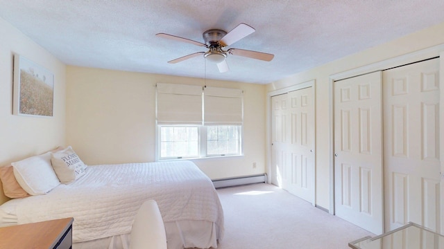 carpeted bedroom featuring a ceiling fan, baseboard heating, two closets, and a textured ceiling
