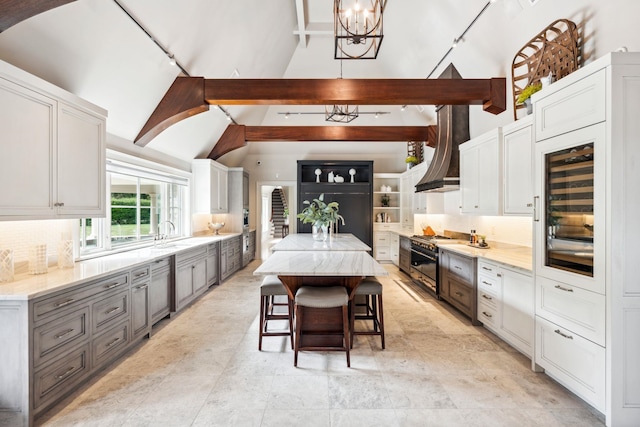 kitchen with gray cabinetry, high vaulted ceiling, range with gas stovetop, and a notable chandelier