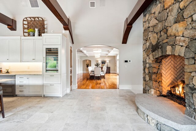 kitchen featuring arched walkways, white cabinets, open floor plan, and visible vents