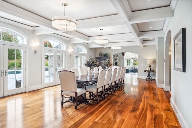 dining space with wood finished floors, a healthy amount of sunlight, a chandelier, french doors, and arched walkways