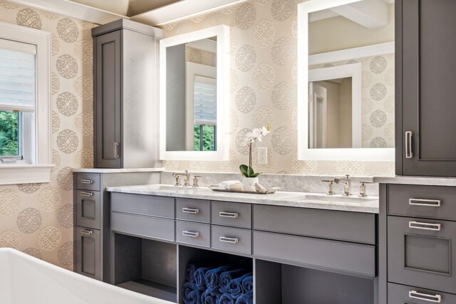 bathroom featuring double vanity, wallpapered walls, and a sink