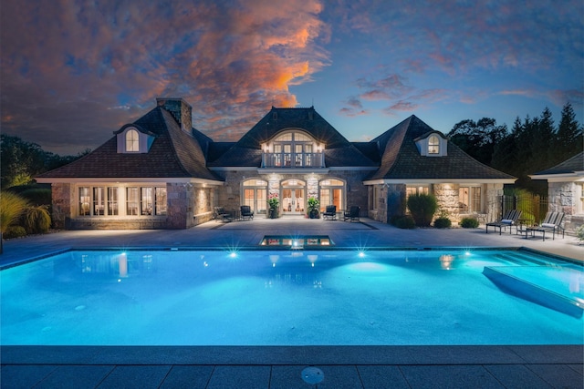 pool featuring french doors, a storage structure, an in ground hot tub, and a patio area