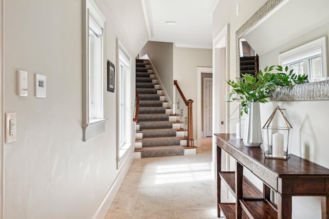 corridor with baseboards, ornamental molding, stairs, and visible vents