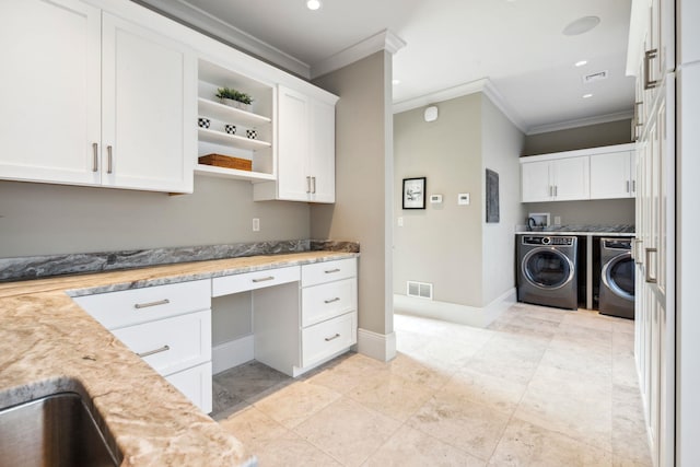 kitchen with visible vents, ornamental molding, built in study area, washer and clothes dryer, and white cabinetry