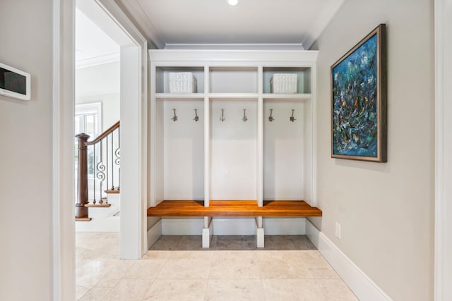 mudroom with tile patterned floors, ornamental molding, and baseboards