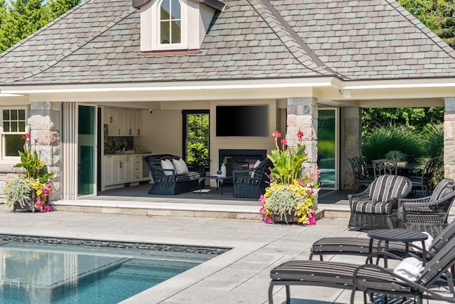 back of property featuring a patio, an outdoor pool, an outdoor living space with a fireplace, and stone siding