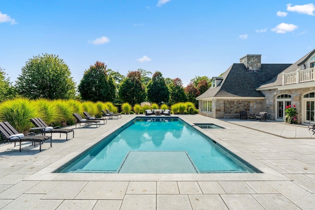 pool featuring a patio and an in ground hot tub