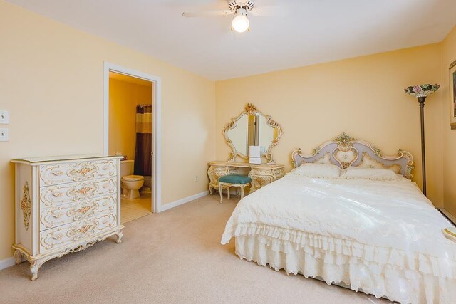 carpeted bedroom with baseboards, a ceiling fan, and ensuite bath