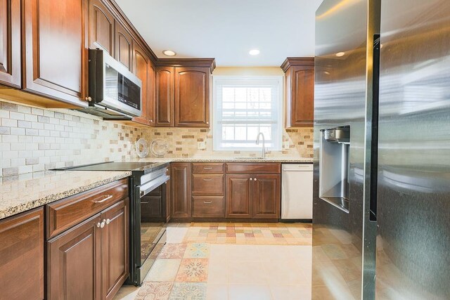 kitchen with backsplash, light stone countertops, a sink, stainless steel appliances, and recessed lighting