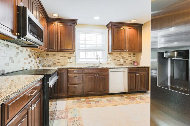 kitchen featuring light stone countertops, a sink, dishwasher, range with electric cooktop, and stainless steel microwave