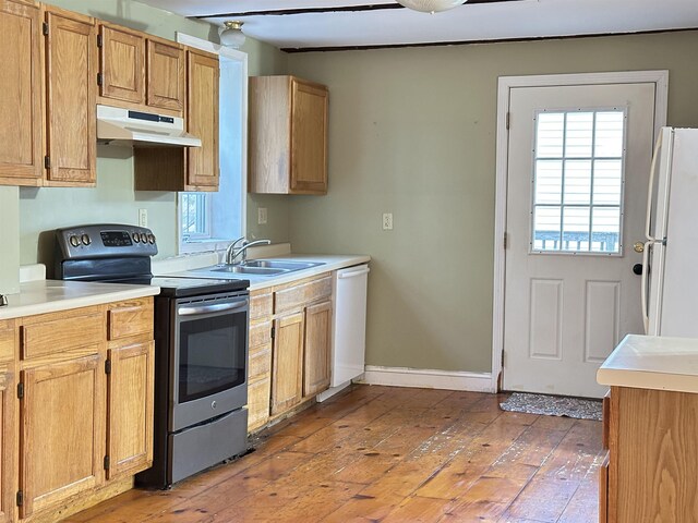 kitchen with a sink, light countertops, under cabinet range hood, white appliances, and light wood-style flooring