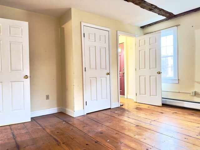 unfurnished bedroom featuring baseboards, baseboard heating, and hardwood / wood-style flooring