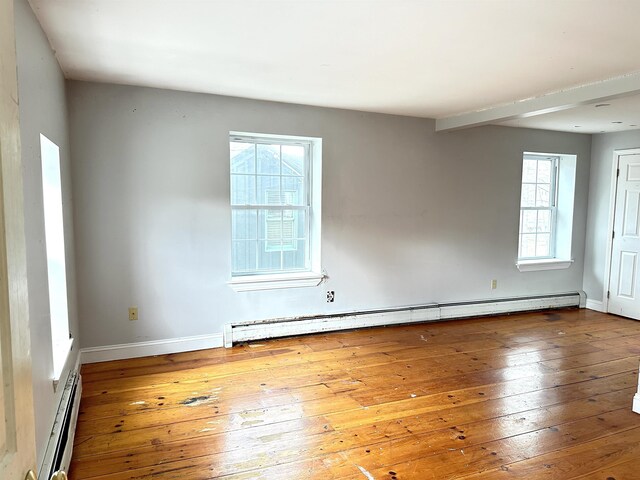spare room with baseboards, a baseboard heating unit, and hardwood / wood-style floors
