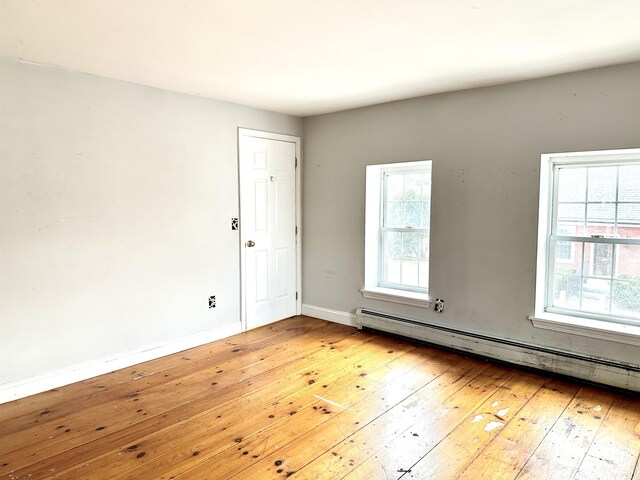 unfurnished room featuring baseboards, baseboard heating, and hardwood / wood-style floors