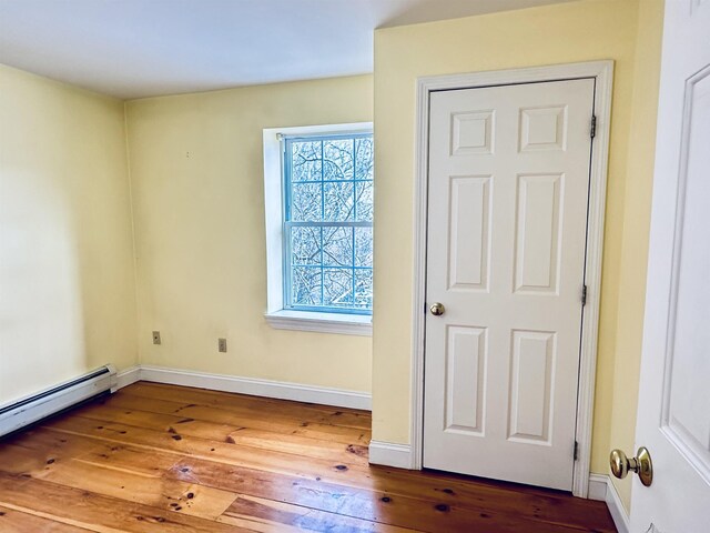 unfurnished bedroom with baseboards, baseboard heating, and hardwood / wood-style floors
