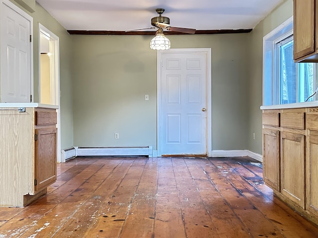 unfurnished dining area with a baseboard heating unit, ceiling fan, dark wood finished floors, and baseboards
