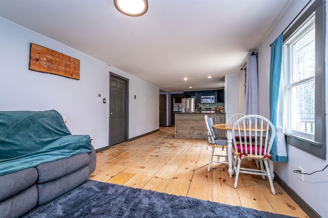 dining room featuring baseboards, light wood-style flooring, and a healthy amount of sunlight