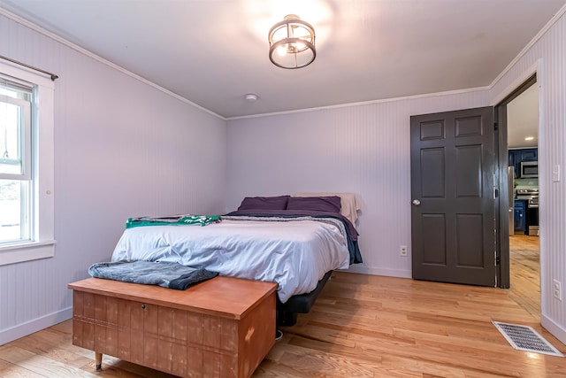 bedroom with light wood-style floors, ornamental molding, baseboards, and visible vents