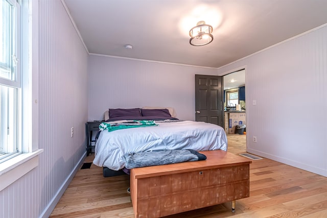 bedroom featuring multiple windows, ornamental molding, and light wood finished floors