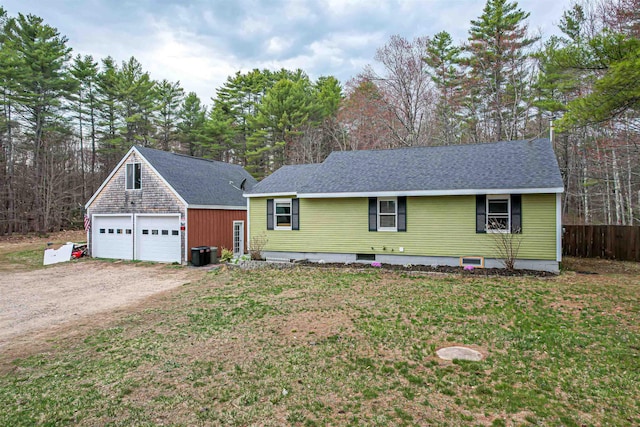 ranch-style home with a detached garage, cooling unit, an outbuilding, and a front yard