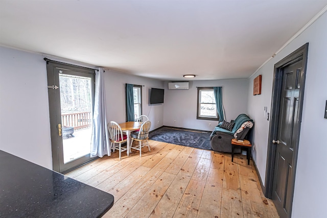 interior space featuring baseboards, an AC wall unit, and light wood-style flooring