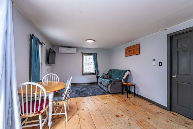 dining area featuring baseboards, light wood-type flooring, and a wall mounted air conditioner