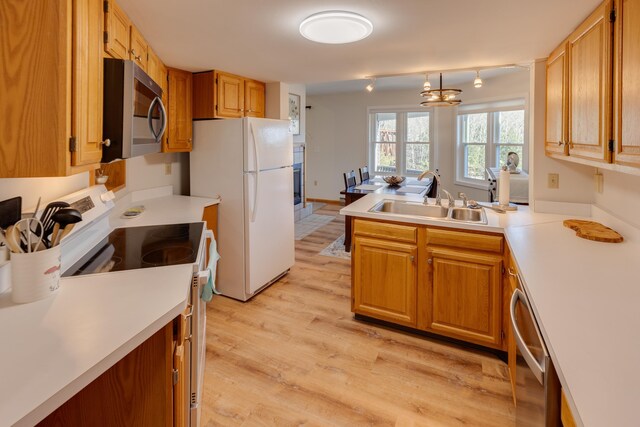kitchen featuring a sink, appliances with stainless steel finishes, light wood-style floors, and light countertops