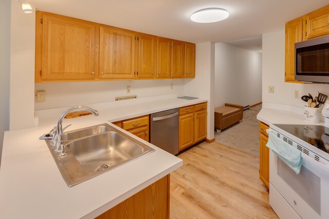 kitchen featuring a sink, light wood-style flooring, appliances with stainless steel finishes, and light countertops