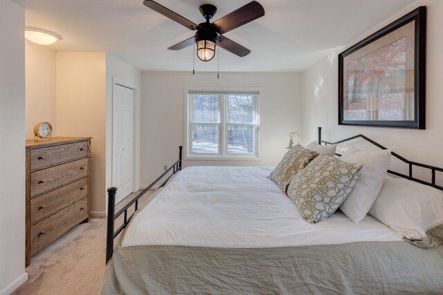 bedroom with light colored carpet, a ceiling fan, baseboards, and a closet