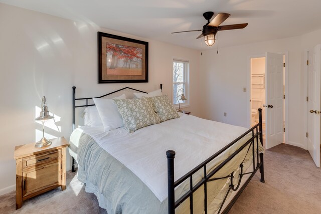 bedroom with a ceiling fan, baseboards, light colored carpet, and a walk in closet