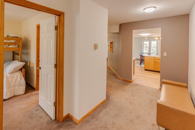 hallway with baseboards and light carpet