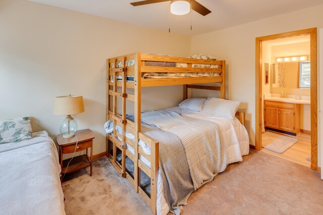 bedroom featuring a sink, ensuite bathroom, ceiling fan, and light colored carpet