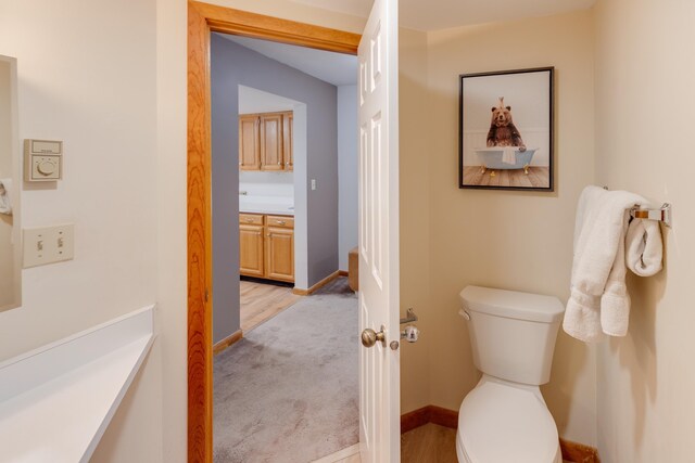 half bath with baseboards, vanity, and toilet